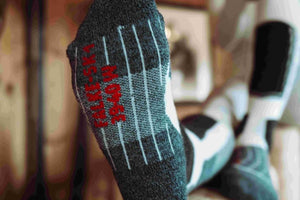 Close-up of a ski sock with red lettering, showing grip features on the sole, perfect for winter sports.