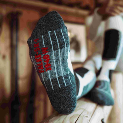 Close-up of a ski sock with red lettering, showing grip features on the sole, perfect for winter sports.