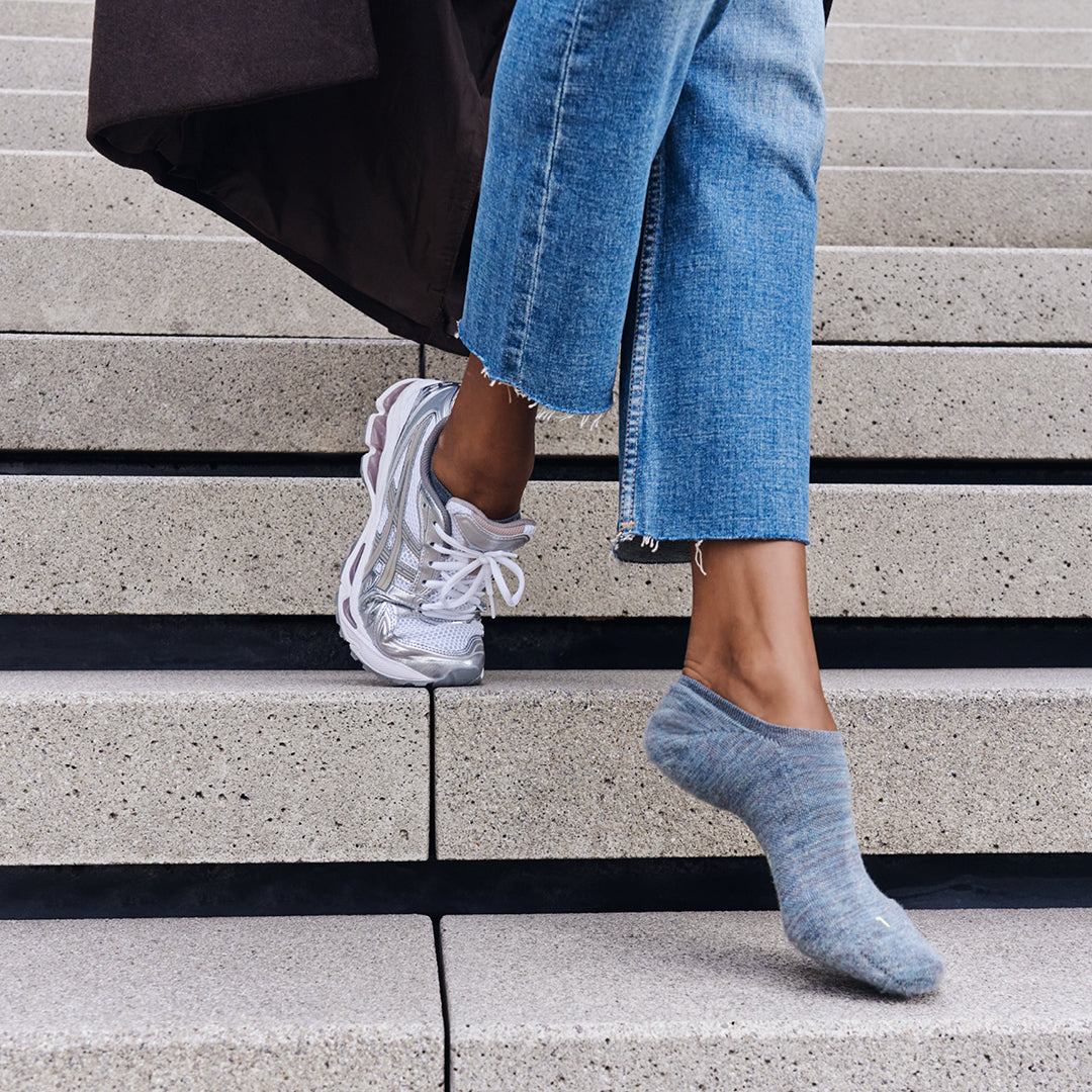 Vrouwelijke voet met FALKE Keep Warm inshoe sokken in sneakers, loop stijlvol naar beneden over trappen.