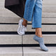 Vrouwelijke voet met FALKE Keep Warm inshoe sokken in sneakers, loop stijlvol naar beneden over trappen.