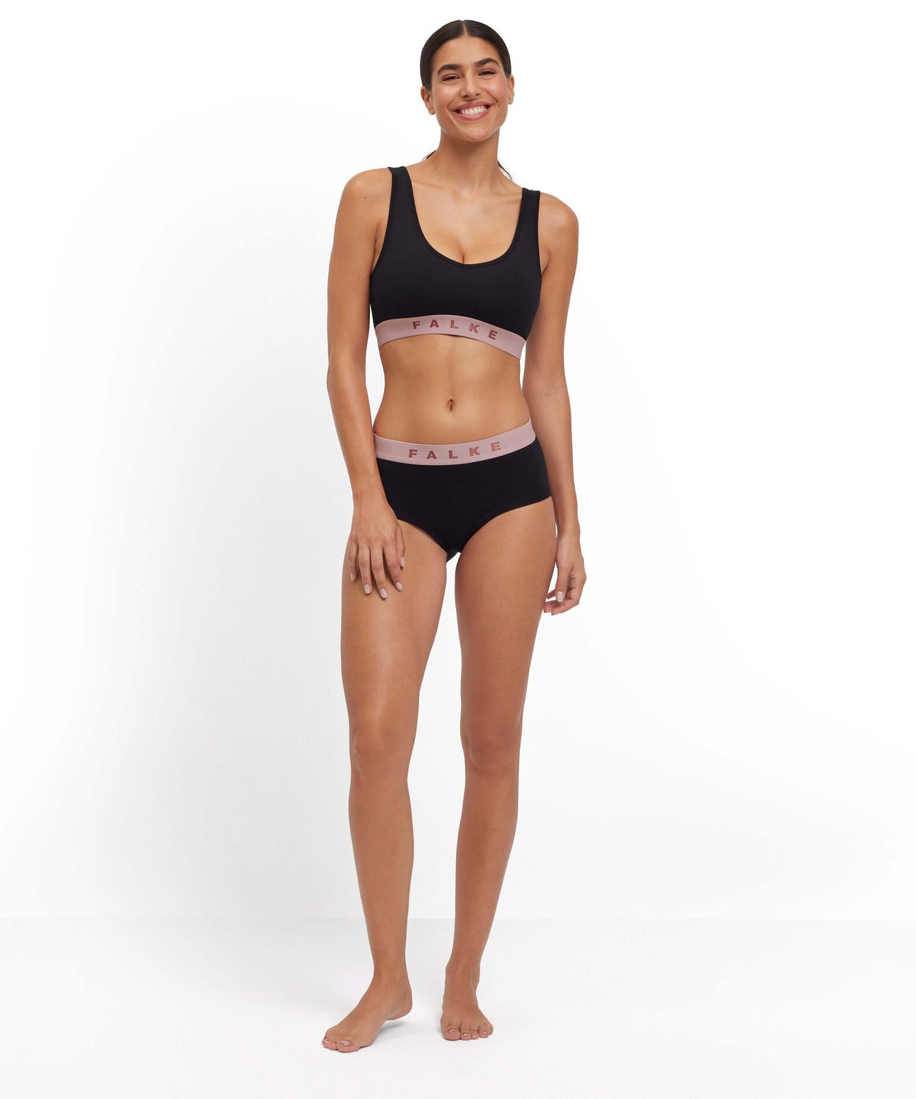 Model draagt de FALKE Hipster en Racerback Top in zwart met roze, voor dagelijks comfort en perfecte pasvorm.