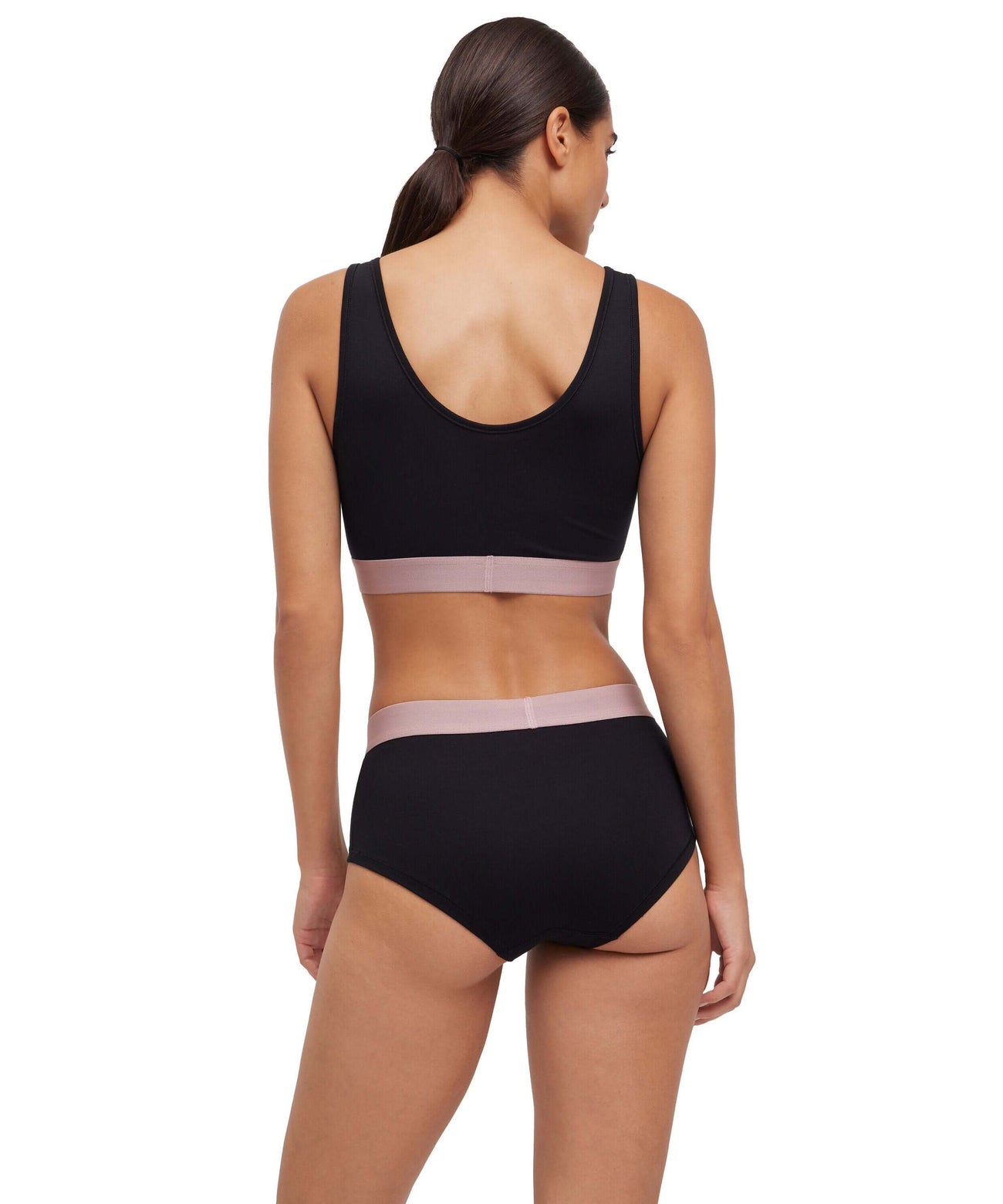 Dame in zwarte hipster en sportbh met roze details, van FALKE voor ultiem comfort en perfecte pasvorm.