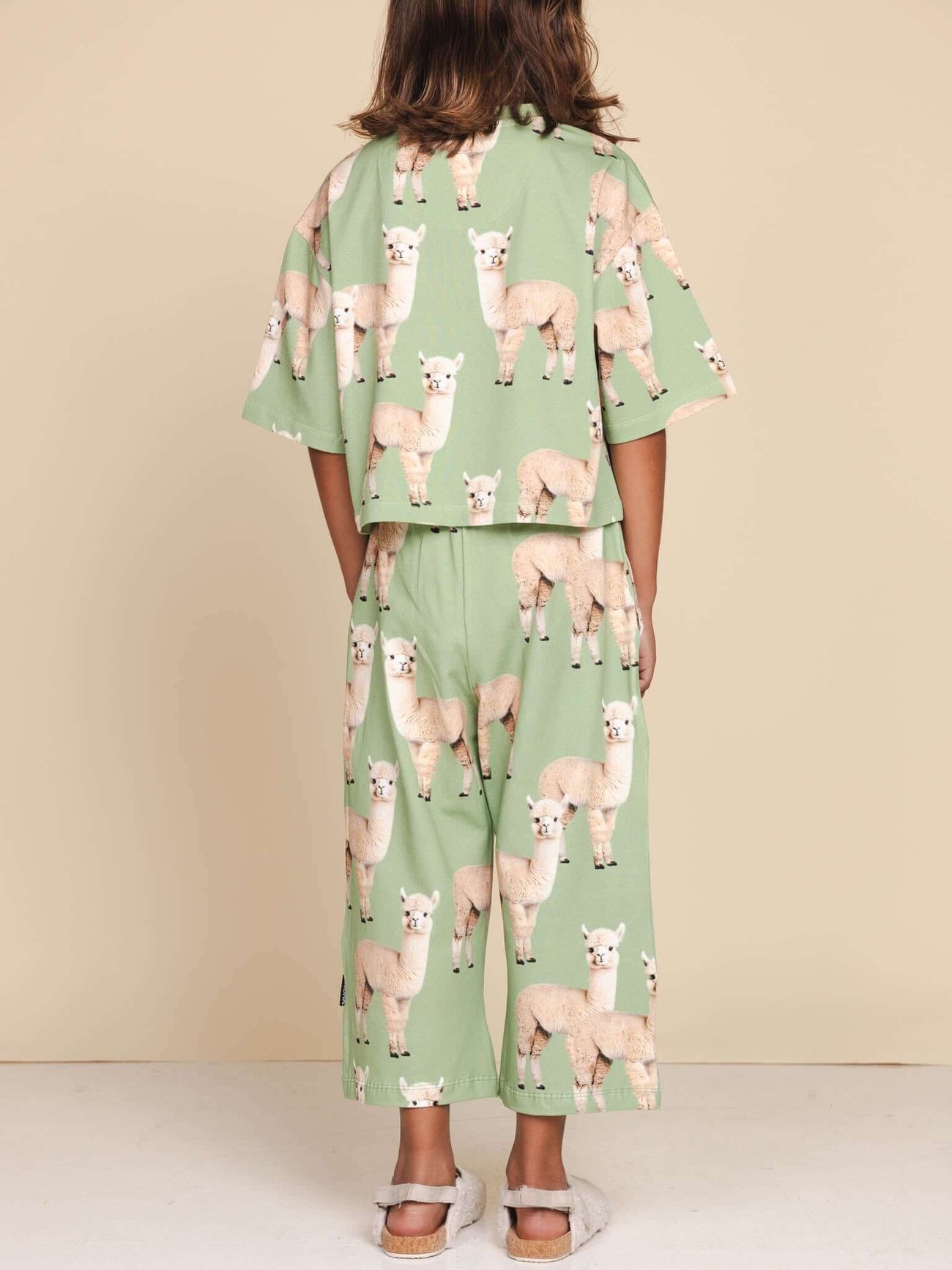 Kind in SNURK Alpaca Meadow Cropped T-Shirt Kids met schattige alpacaprint, ontspannen fit en korte mouwen.