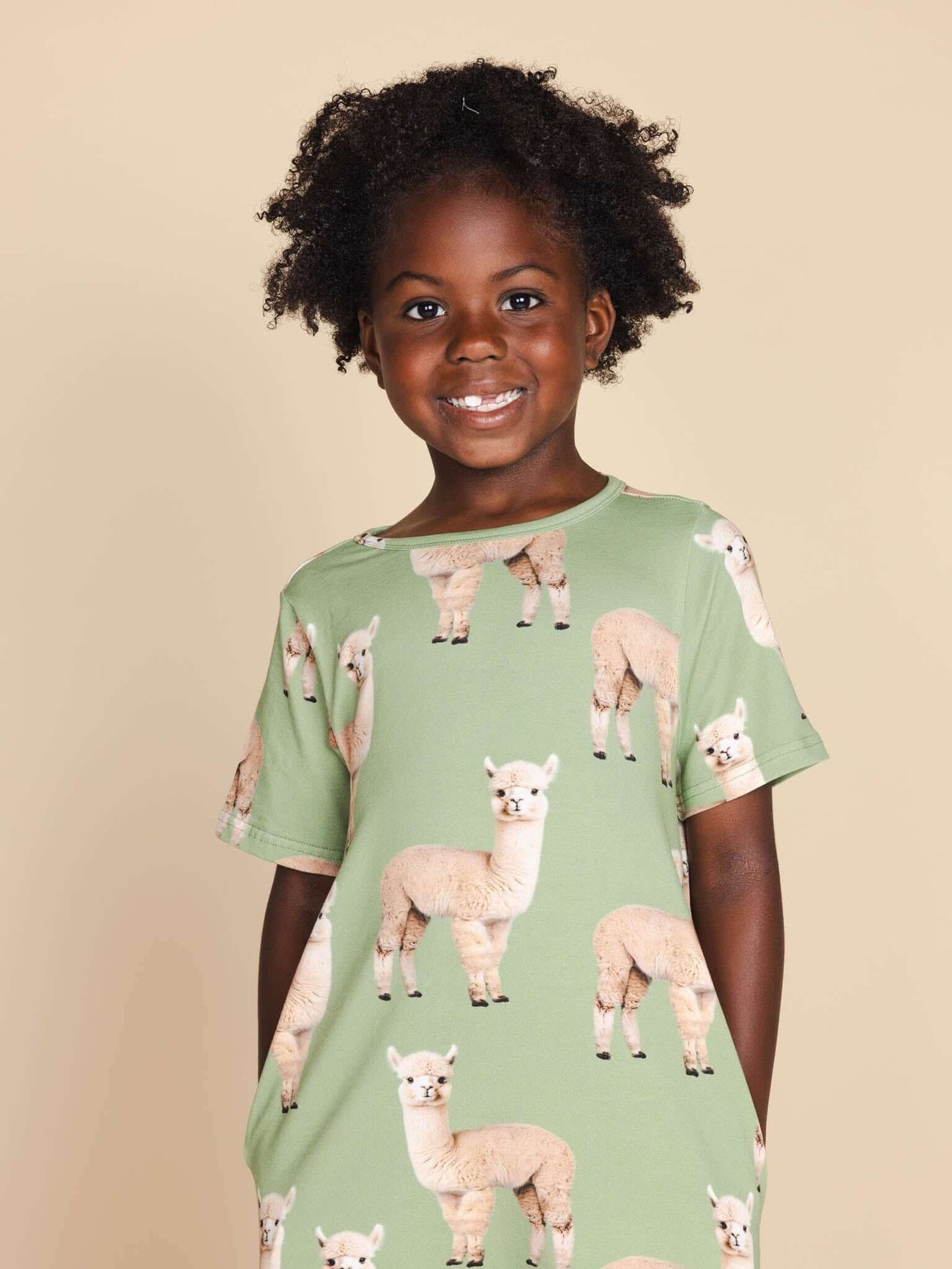 Kind geniet in een SNURK Alpaca Meadow T-shirt Dress Kids met schattige alpaca print.
