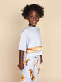 SNURK Baguette Cropped T-Shirt Kids met een vrolijk kind in een pyjama met croissantmotief.