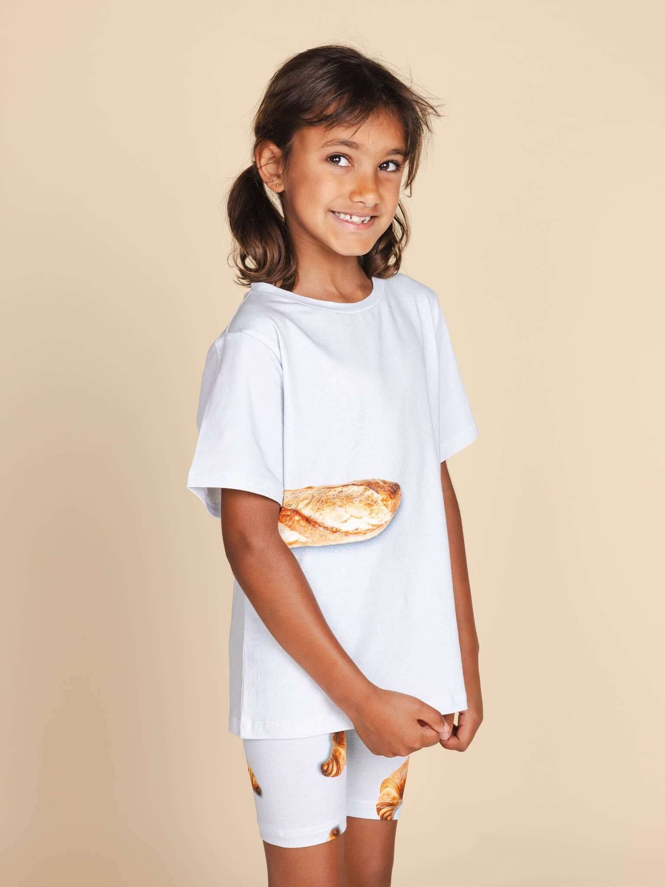 Kind in SNURK Baguette T-shirt Kids met stokbroodje op de voorkant, gemaakt van biologische katoen.
