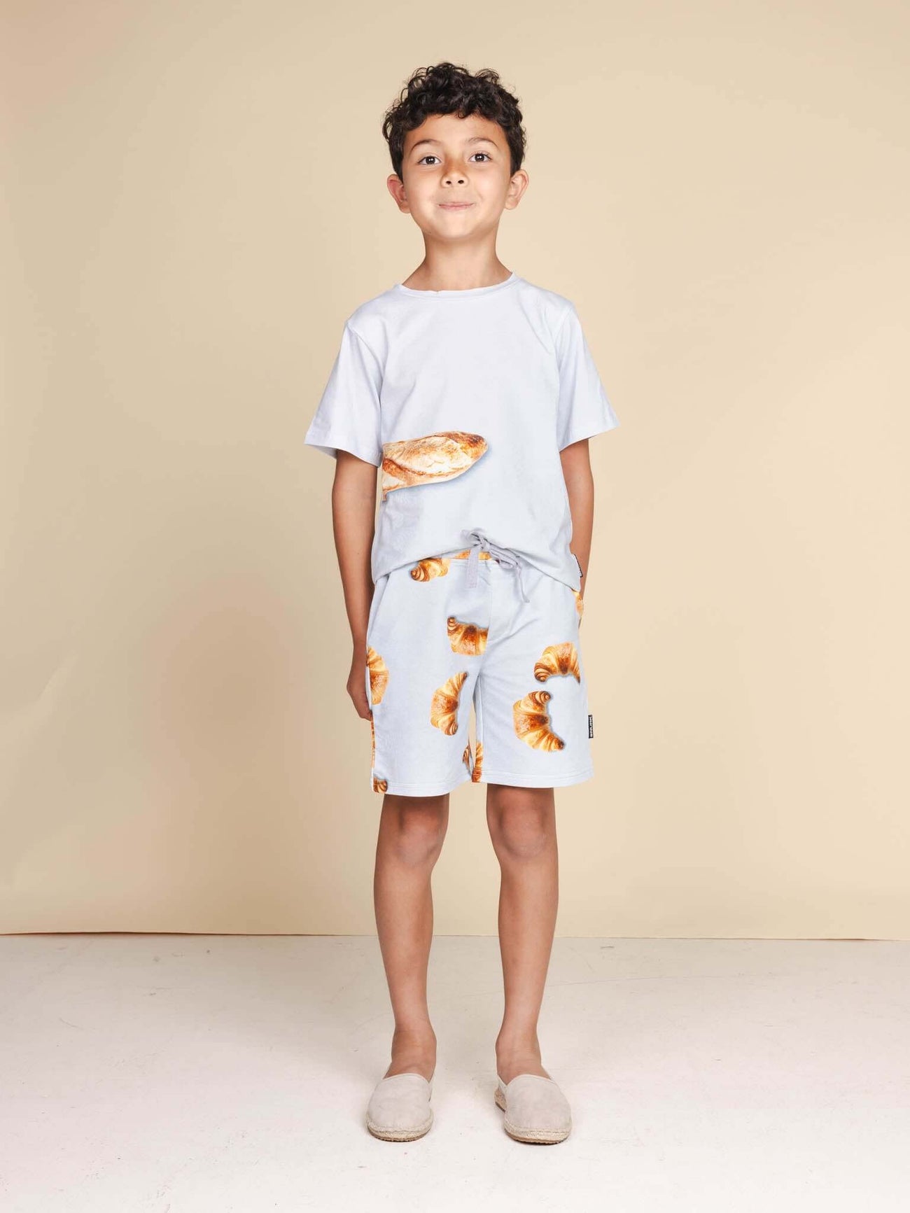 Jongen in SNURK Baguette T-shirt Kids met stokbroodje en korte broek, ideaal voor kinderen.