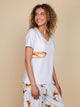 Model in SNURK Baguette V-Neck T-shirt Dames met stokbroodje print, perfect voor ontspannen dagen.