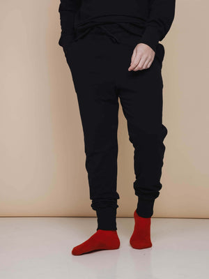 SNURK Black Broek Regular Unisex, zwarte joggingsbroek met rode sokken, ideaal voor thuis en na het sporten.