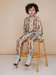 SNURK Bowie Broek Kids model met kattenprint zittend op een houten kruk in kinderkleding.