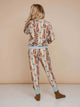 Achteraanzicht van een kindermodel in de SNURK Bowie Broek Kids met kattenprint op een beige achtergrond.