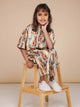 Kind in SNURK Bowie Cropped T-Shirt Kids met katjesprint, zittend op een stoel.