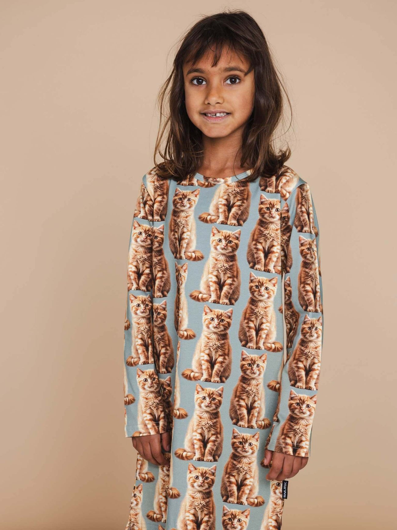 Meisje in SNURK Bowie Long Sleeve Dress Kids met schattige kattenprint en lange mouwen.