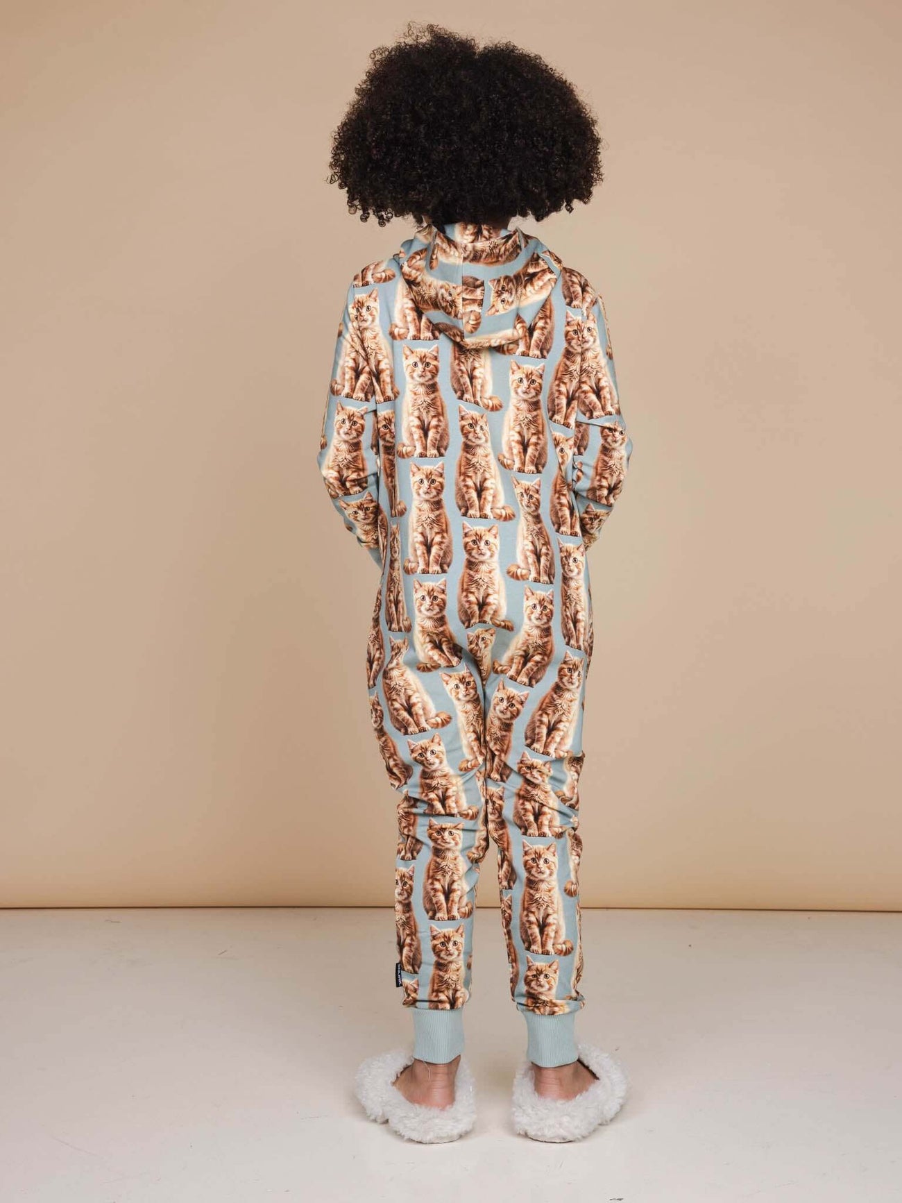 Kind in SNURK Bowie Onesie Kids met een schattige kattenprint, perfect om in te slapen en te chillen.
