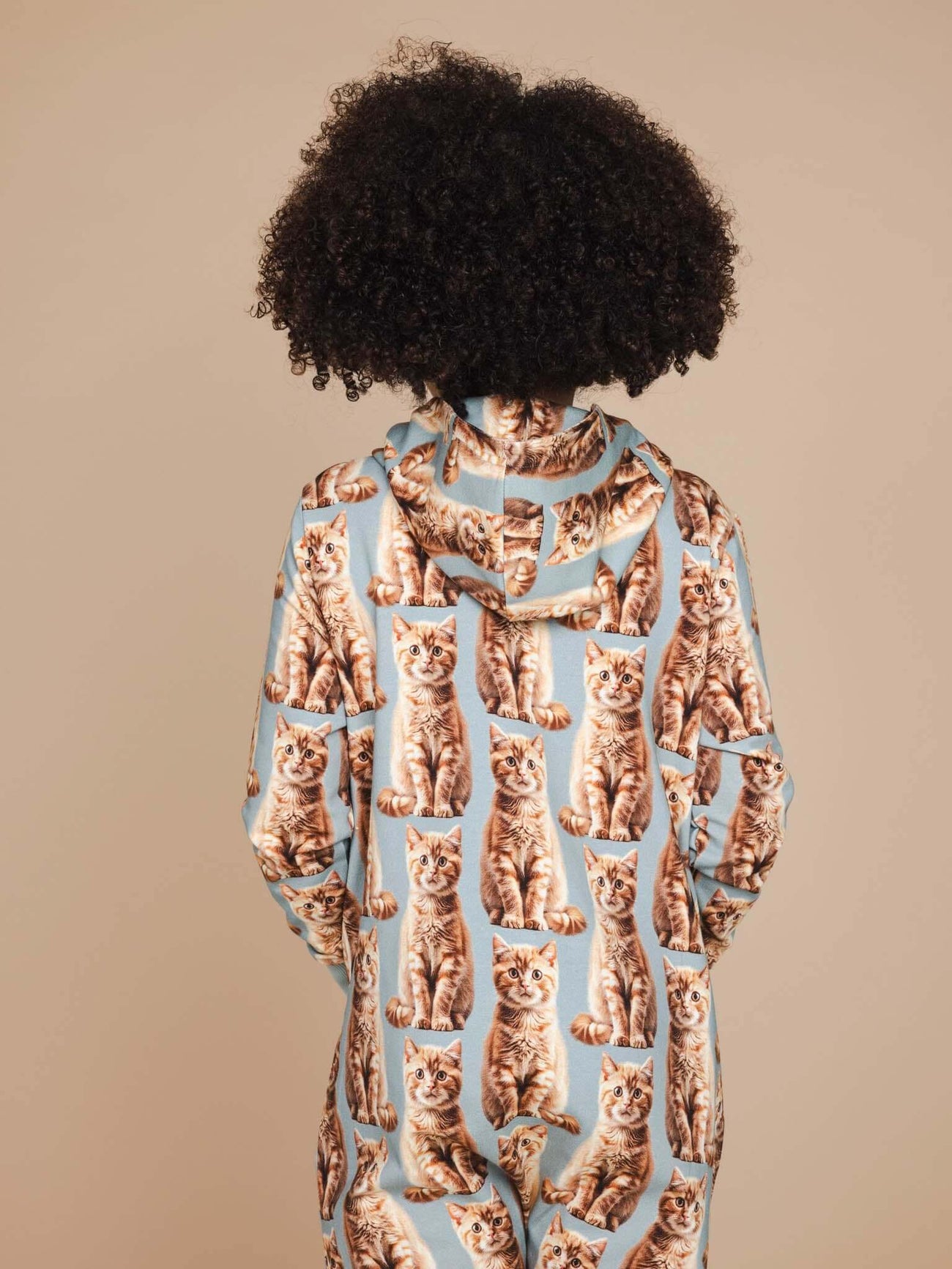 Kind in SNURK Bowie Onesie Kids met kattenprint, perfect voor spelen en slapen.