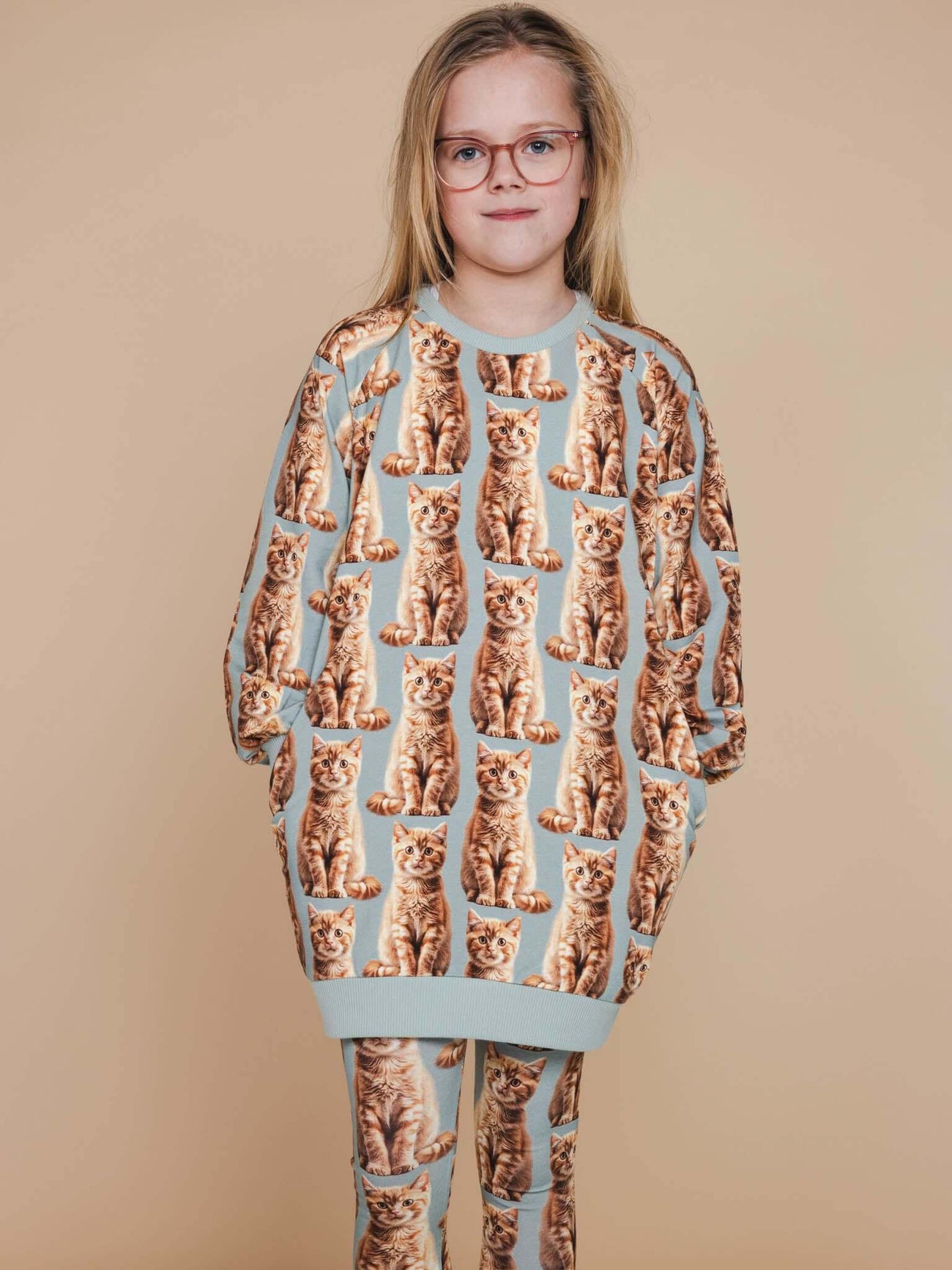 SNURK Bowie Sweater Dress Kids worn by a girl with cat print and matching leggings, perfect for comfort and chilling.