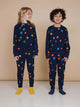 Kinderen in SNURK Building Blocks Broek Kids met kleurrijke blokken print op een donkerblauwe achtergrond.
