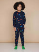 Kind in SNURK Building Blocks Onesie Kids met kleurrijke blokken op een donkerblauwe achtergrond.