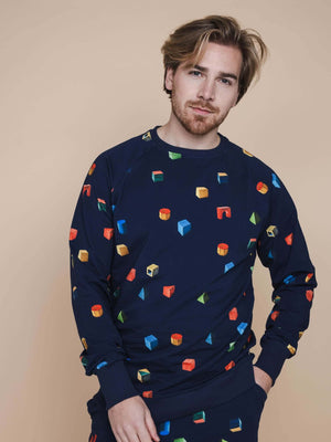 SNURK Building Blocks Sweater Heren met kleurrijke blokken op een navy achtergrond, model poseert met een relaxte uitstraling.