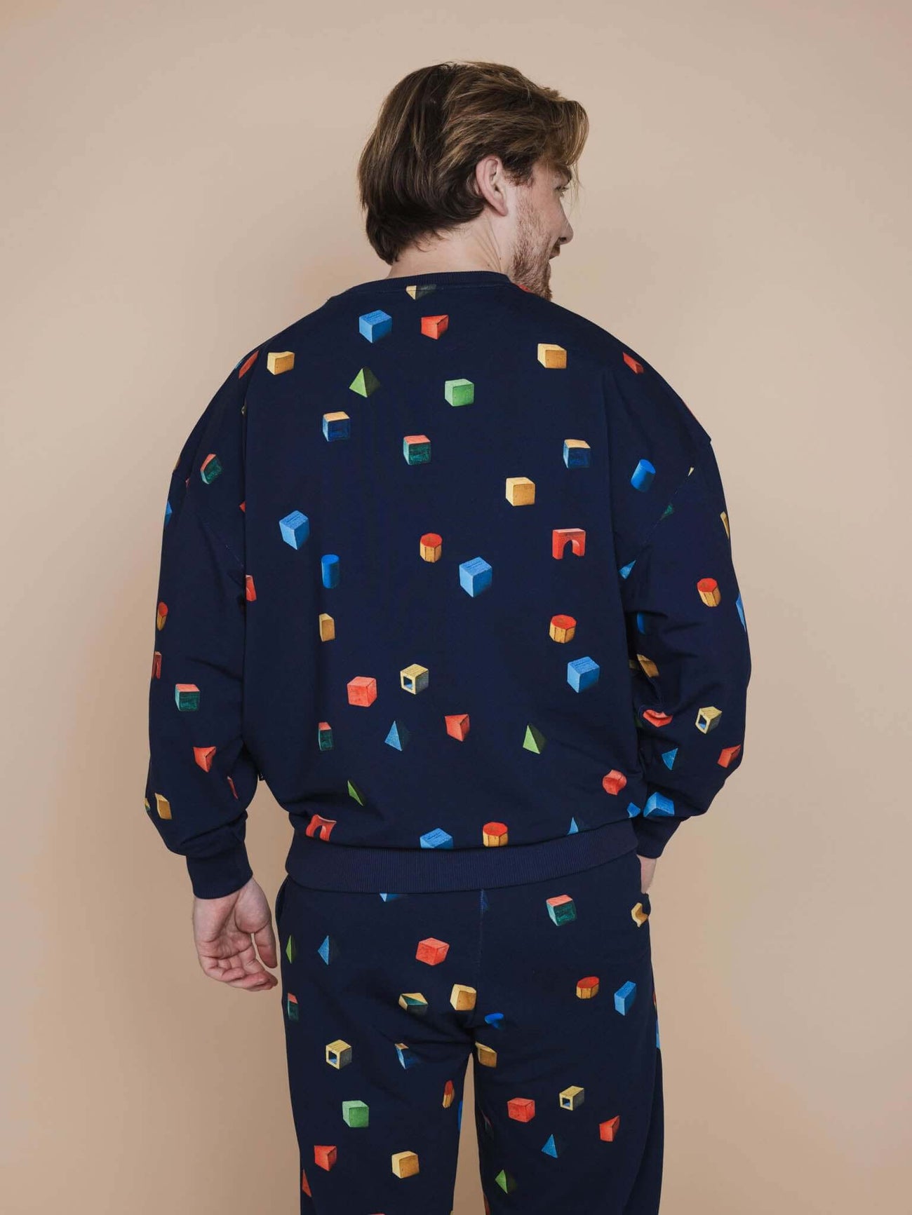 SNURK Building Blocks Sweater Heren met kleurrijke blokkenprint op een navy achtergrond, casual herenoutfit.