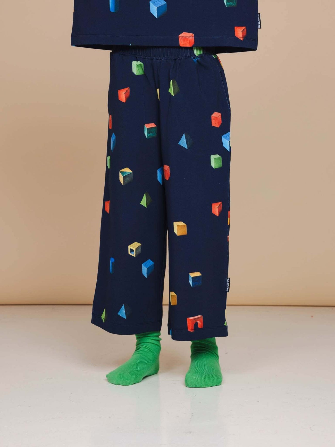 SNURK Building Blocks Wijde broek Kids met kleurrijke blokken op een donkerblauwe achtergrond.