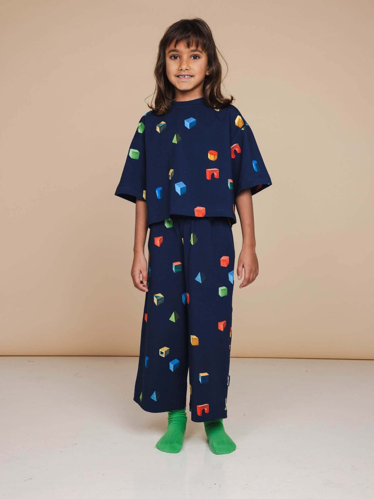 SNURK Building Blocks Wijde broek Kids outfit met kleurrijke blokken op donkerblauwe achtergrond.