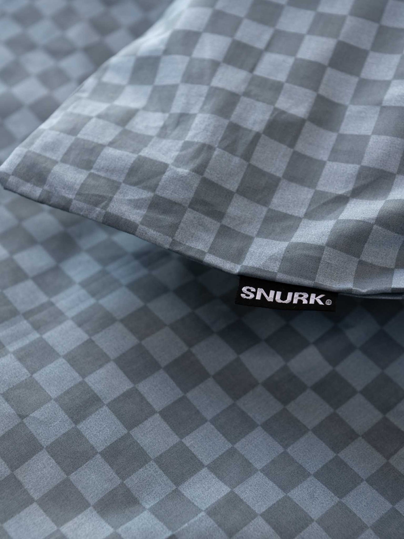SNURK Check Faded Blue dekbedovertrek met ruitpatroon en label op de kussensloop.