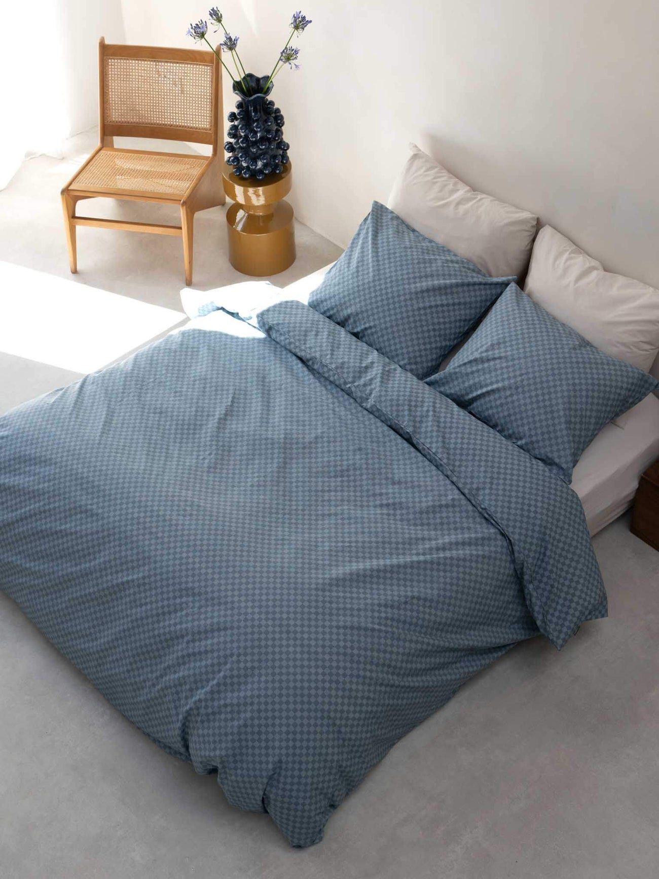 SNURK Check Faded Blue dekbedovertrek op een bed met kussens, geeft een vrolijke touch aan de slaapkamer.