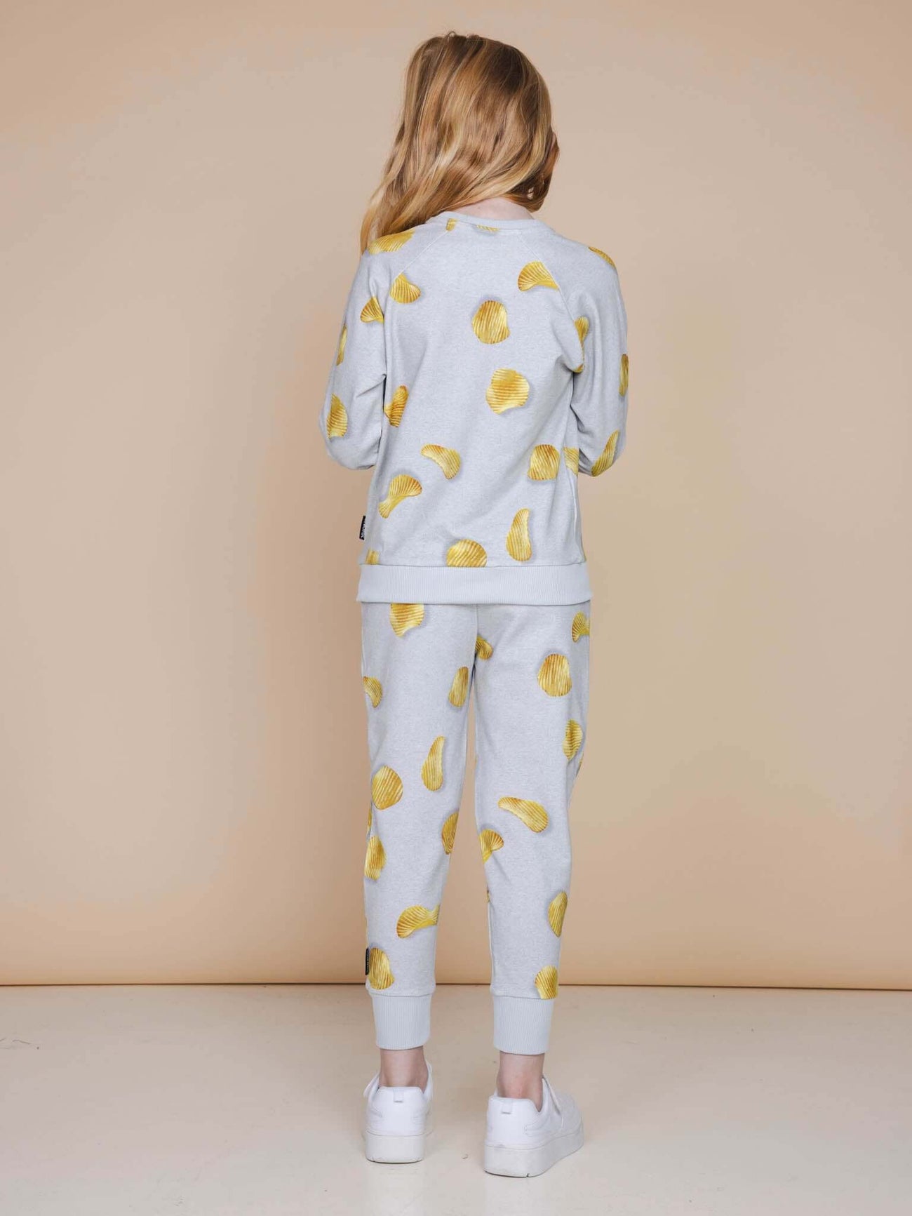 Achteraanzicht van een meisje in een lichtgrijze SNURK Chips Broek Kids met een chippies print.
