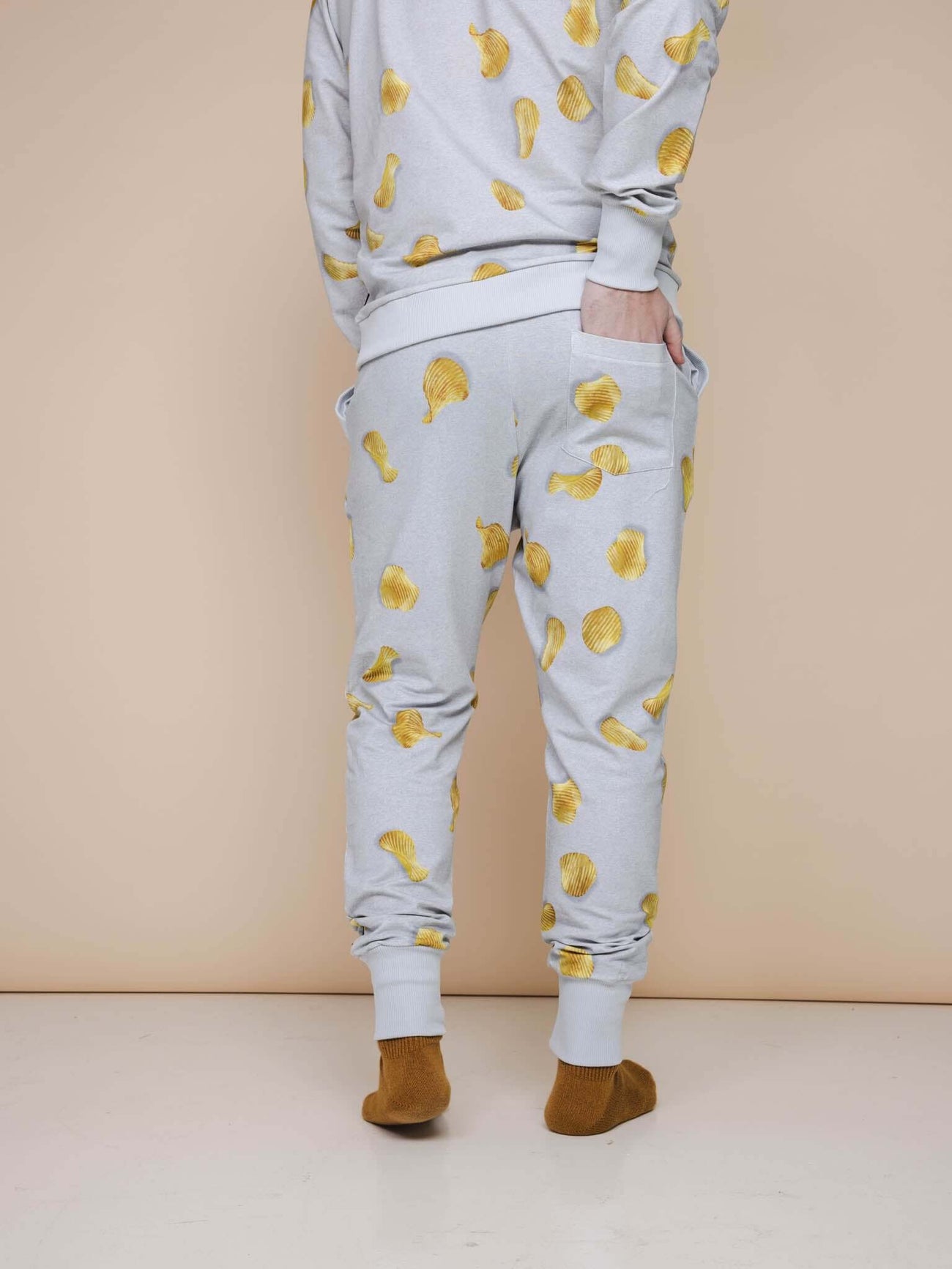 SNURK Chips Broek Regular Unisex met chipsprint op een lichtgrijze achtergrond, perfect voor comfort en stijl.