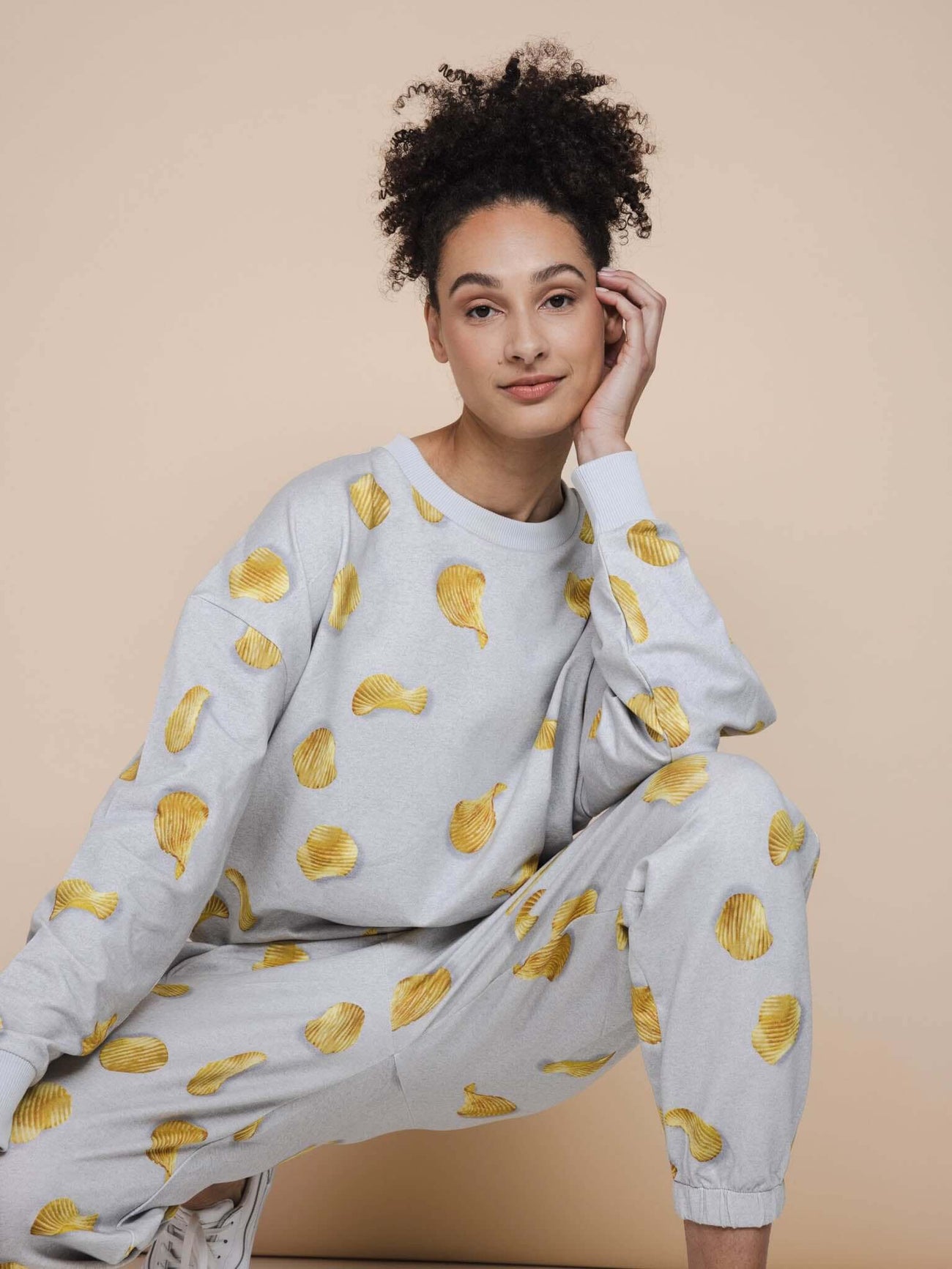 SNURK Chips Broek Relaxed Unisex model in lichtgrijze broek met chipsprint, casual pose, zachte biologische katoen.