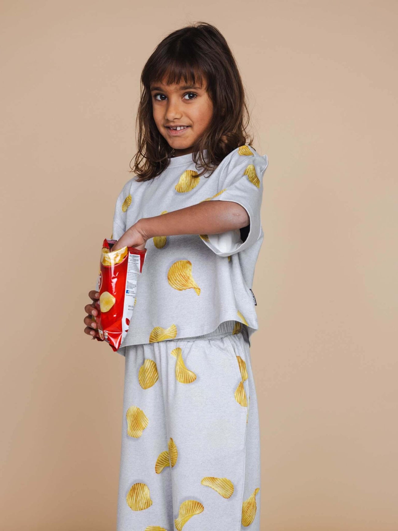 Kind in SNURK Chips Cropped T-Shirt Kids met chippies, perfect voor speel- en bedtijd.