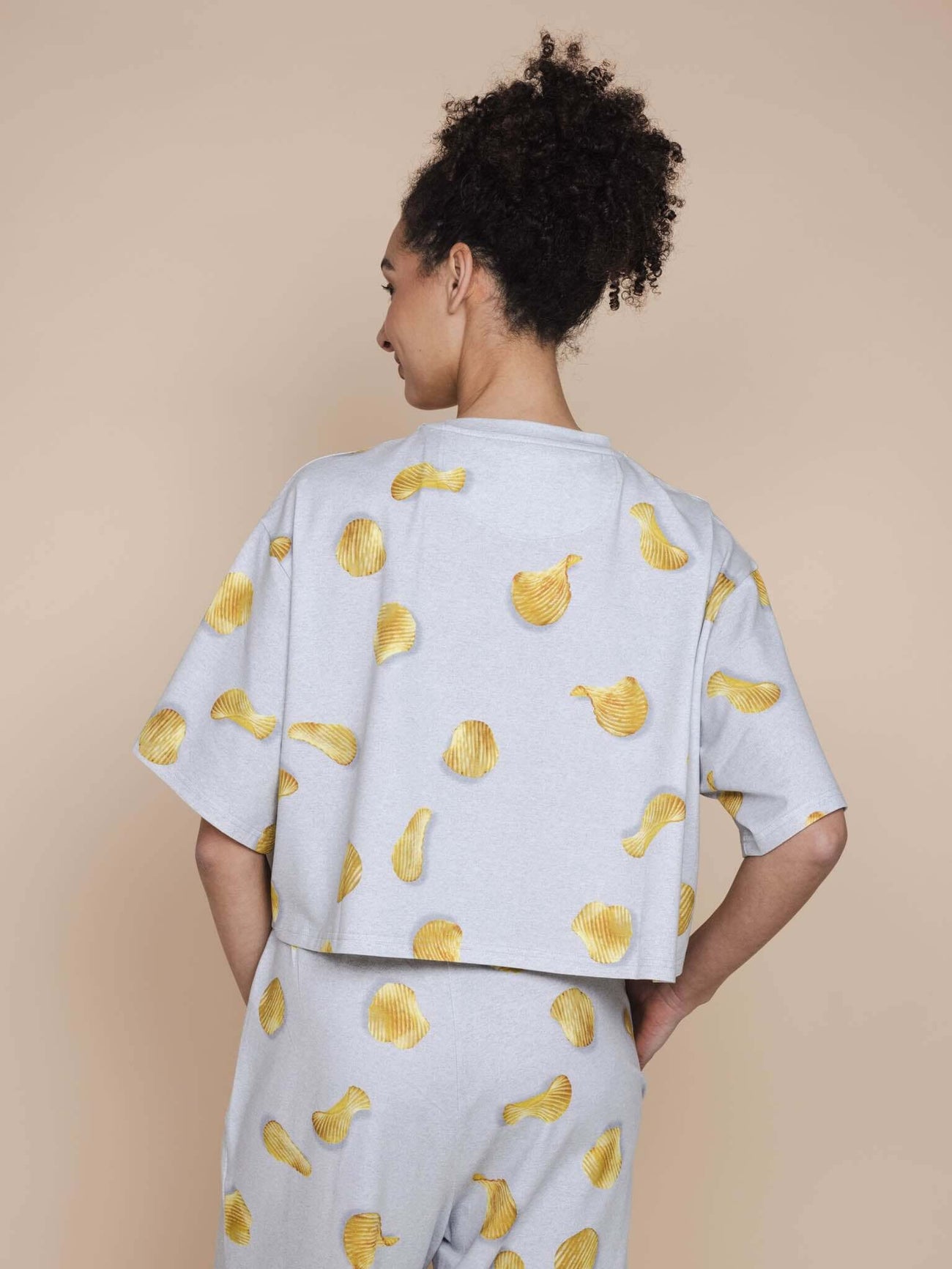 SNURK Chips Cropped T-shirt Dames met chipsprint op een lichtgrijze achtergrond, perfect voor relaxen.