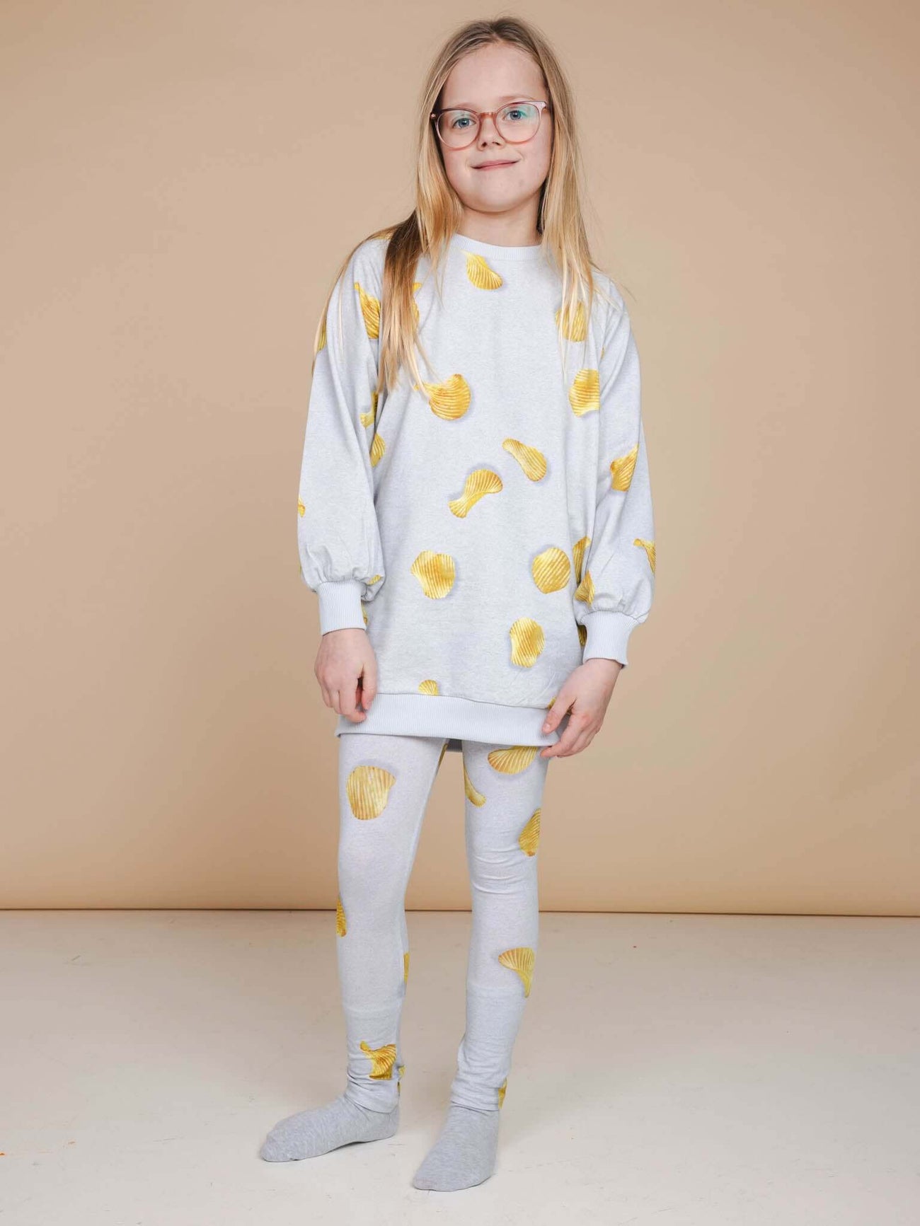 SNURK Chips Legging Kids gedrapeerd met een comfortabele sweater en leuk chips ontwerp op een lichte achtergrond.