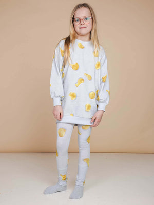 SNURK Chips Legging Kids gedrapeerd met een comfortabele sweater en leuk chips ontwerp op een lichte achtergrond.