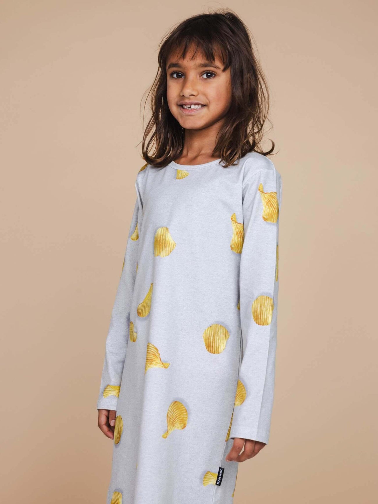 SNURK Chips Long Sleeve Dress Kids, meisje in lichtgrijze jurk met chipsprint, casual look.