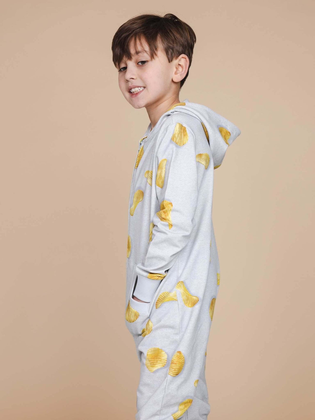 SNURK Chips Onesie Kids model in lichtgrijze onesie met chipsprint, perfect om te slapen en te chillen.