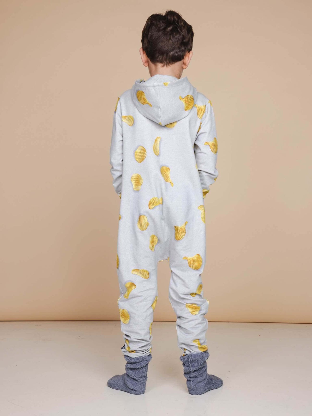Kind in SNURK Chips Onesie Kids met chipjesprint, ideaal om in te slapen en te chillen.