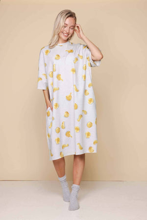 SNURK Chips Relaxed Tee Dress Dames met naturel chips print op een lichtgrijze achtergrond, gedragen door een vrouw.