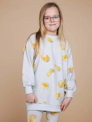 SNURK Chips Sweater Dress Kids met een all-over print van chips op een lichte achtergrond.