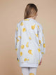 A child wearing the SNURK Chips Sweater Dress Kids featuring a playful all-over print of chips on a light grey background.