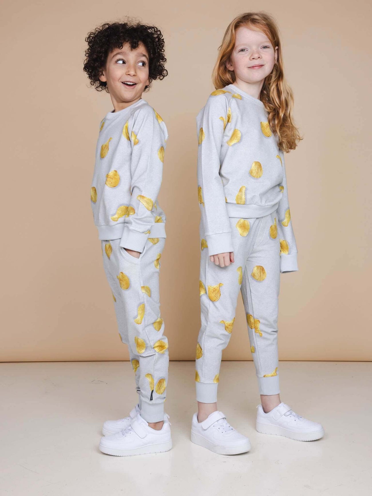 SNURK Chips Sweater Kids in lichtgrijs met chippies print, kinderen poseren in relaxte outfit.