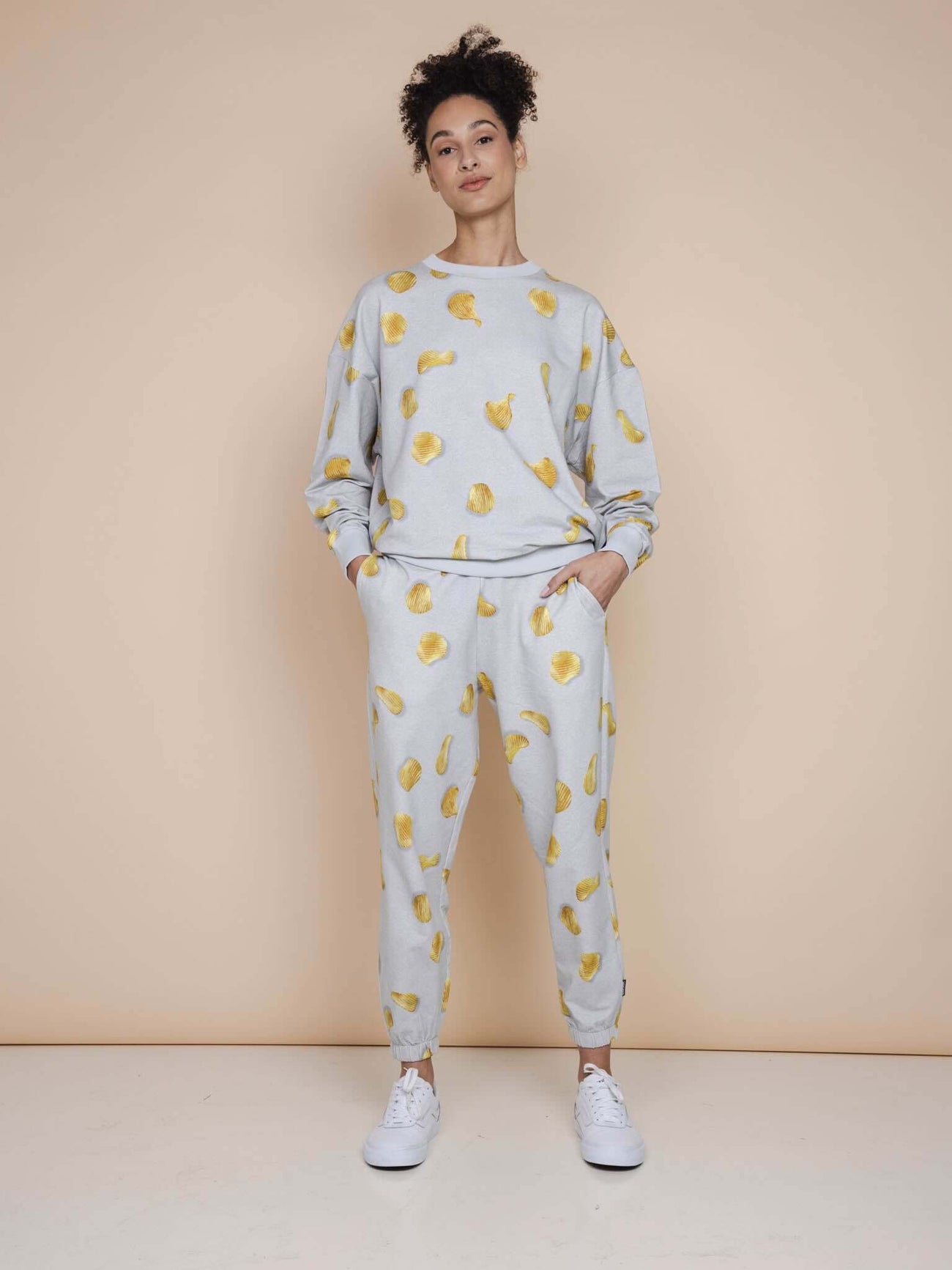 SNURK Chips Sweater Unisex met naturel chips print op een lichtgrijze basis, model met relaxed-fit outfit.