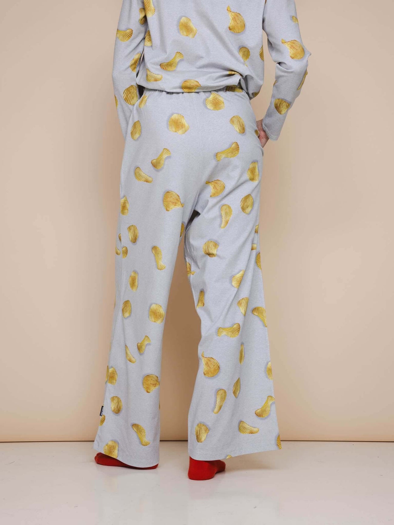 Achteraanzicht van de SNURK Chips Wijde broek Dames met een all-over chips print op een lichtgrijze basis.