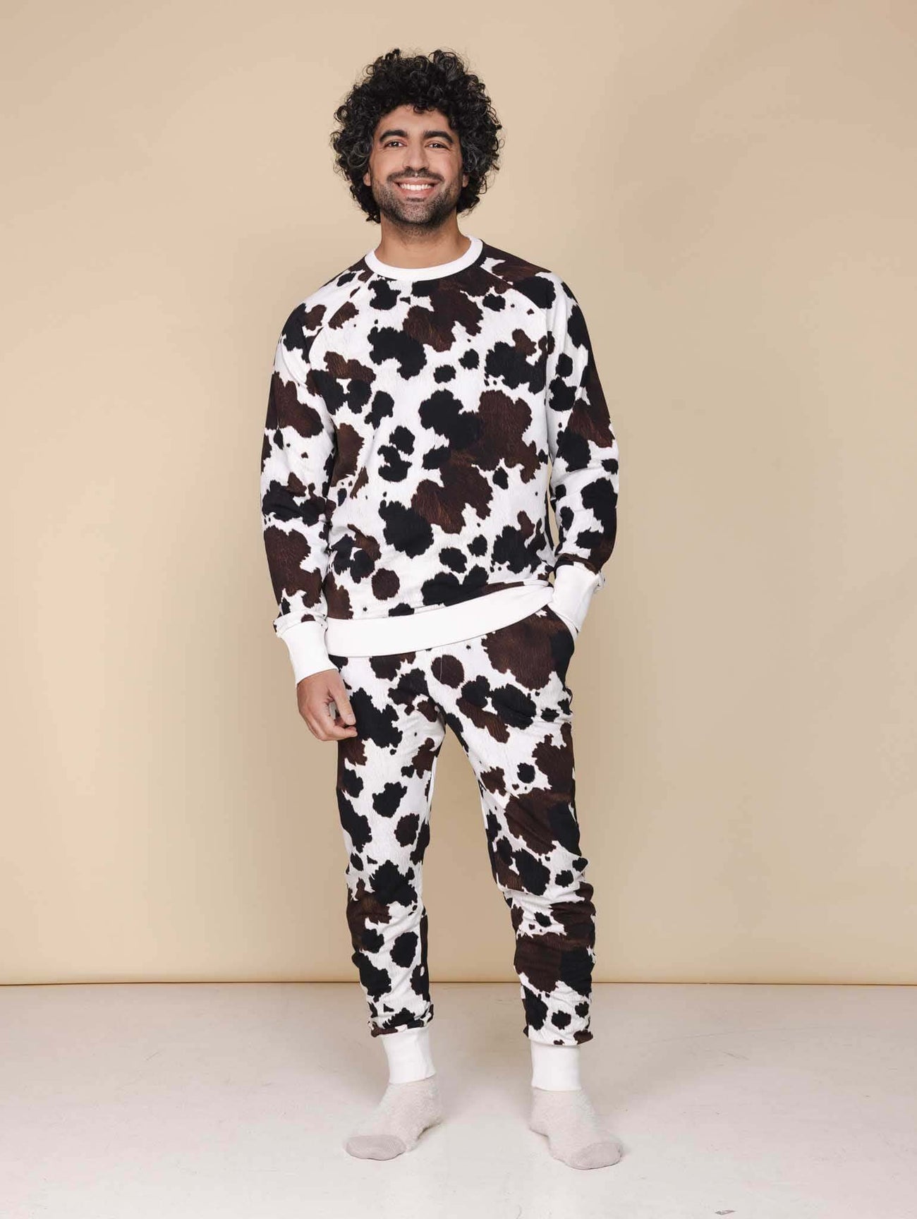 SNURK Cow Broek Unisex - man in comfortabele joggingbroek met koeienhuidprint en trui, ideaal voor thuis of na het sporten.