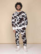 SNURK Cow Broek Unisex - man in comfortabele joggingbroek met koeienhuidprint en trui, ideaal voor thuis of na het sporten.