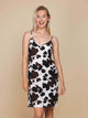 SNURK Cow Strap Dress Dames op vrouw met spaghettibandjes en koeienhuidprint tegen een neutrale achtergrond.