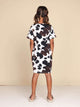 Achteraanzicht van een meisje in een SNURK Cow T-shirt Dress Kids met een stoere koeienprint.