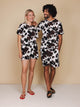 SNURK Cow T-shirt Unisex modelled by a couple wearing matching cow print outfits.