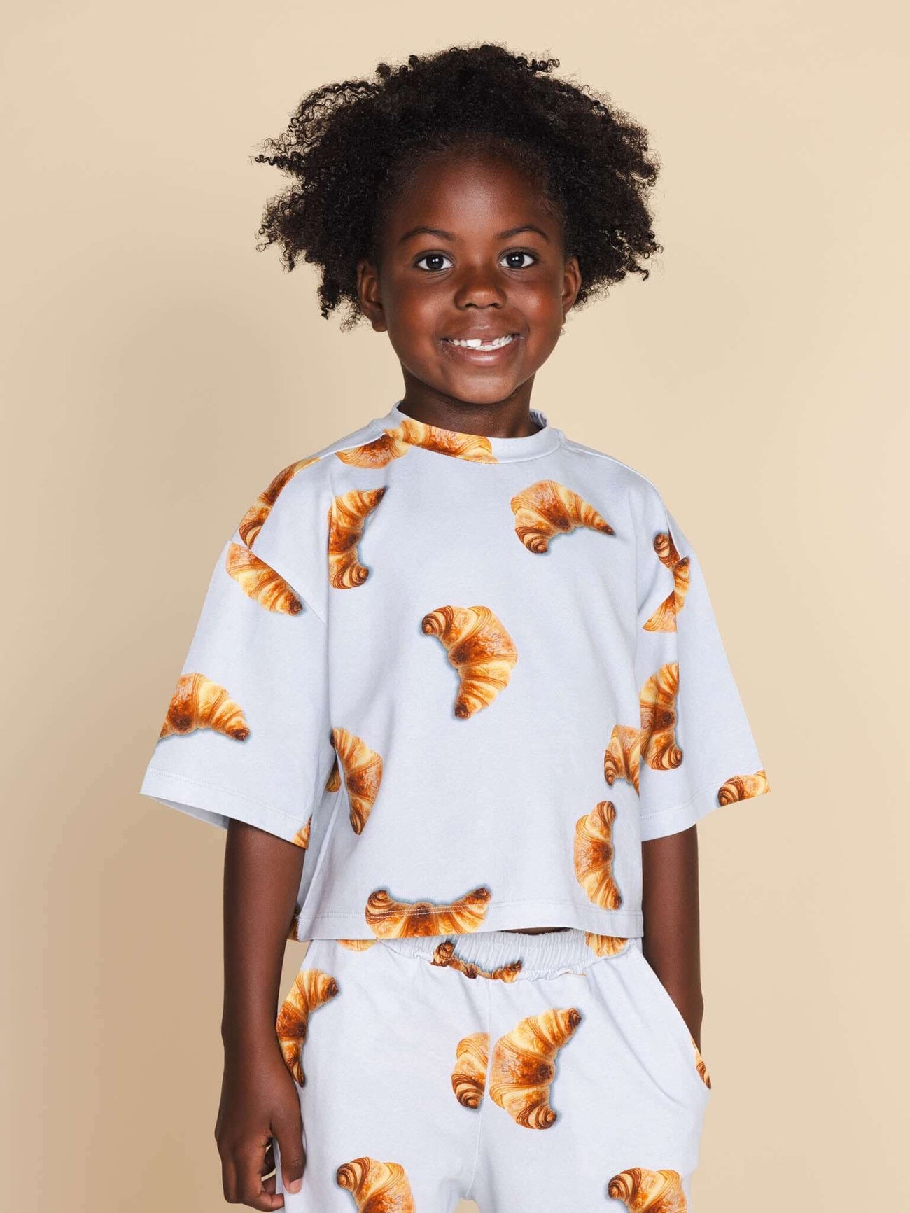 SNURK Croissants Cropped T-Shirt Kids met vrolijke croissantjes, perfect voor kinderen die van comfort houden.